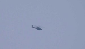 Un hélicoptère lance des fusées éclairantes alors que la fumée s'élève au-dessus de Gaza
