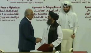 Poignée de mains entre le négociateur américain et le chef politique des talibans après la signature de l'accord