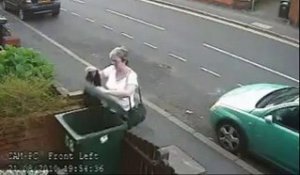 Une femme jette un chat à la poubelle