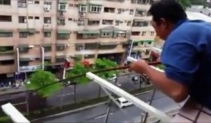Un homme pêche depuis son balcon au 5eme étage d'un batiment