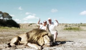 Un couple de chasseurs prend la pause devant un lion mort