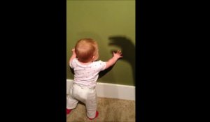 Ce bébé jour avec l'ombre chinoise de la main de sa maman au mur...