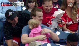 Ce spectateur attrape une balle de baseball tout en tenant sa fille et de la nourriture dans les bras