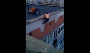 Le gars se suspend dans le vide au sommet d'un immeuble et fait des tractions
