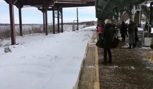 Un train éclabousse de neige des voyageurs qui attendaient sur le quai