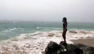 Une fille fait la belle au bord de la mer et finit par se prendre une vague !