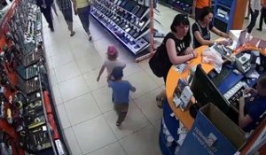 2 enfant essaient de voler un iPad relié à un cable de sécurité sous les yeux du vendeur