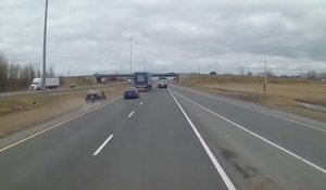 Un automobiliste impatient passe par l'herbe pour doubler deux camions sur l'autoroute