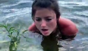 Une femme attrape une créature terrifiante sortant du fond d'un lac avec ses mains nues