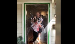 Une fillette installe un rideau en plastique devant chez ses grands-parents pour pouvoir les enlacer