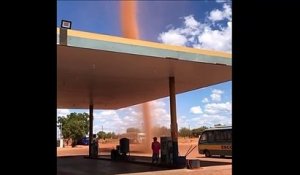 Une mini tornade de sable passe juste à côté d'une station essence