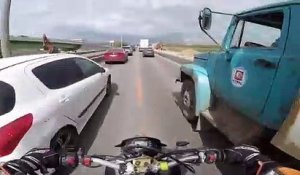 Un motard double un camion par la droite