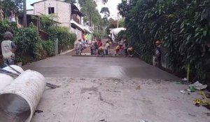 Il marche sur le béton frais que viennent de couler ces ouvriers