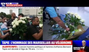 Mort de Bernard Tapie: des Marseillais écrivent des mots sur l'affiche placée devant le Vélodrome et déposent des fleurs en hommage