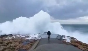 Un cycliste se rapproche un peu trop près du bord de mer pendant la tempête