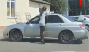 Une femme utilise les vitres d'une voiture comme miroir