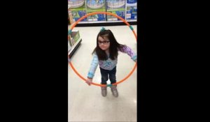 Une petite fille essaie de faire du hula hoop. Trop mignon