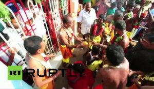 Des prêtres indiens brisent des noix de coco sur la tête des croyants