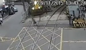 Un vieil homme traverse une voie ferrée juste devant un train