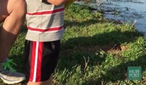 Un gamin attrape un gros poisson avec sa canne à pêche jouet.