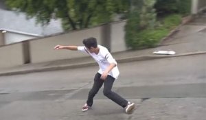 Un gars arrive à faire du skate sans skate sur une route mouillée