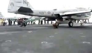 Un soldat emporté par le souffle d'un réacteur d'avion au décollage sur un porte-avion