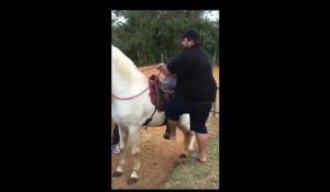 Un homme a beaucoup de mal à monter sur un cheval !
