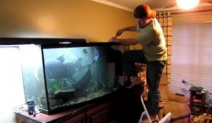 Il essaie de capturer son gros poisson pour le changer d'aquarium