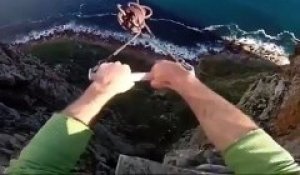 Un homme fait un saut pendulaire du haut d’un rocher et lâche la corde pour sauter dans le vide