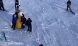 Un snowboardeur suspendu à son télésiège, secouru par un autre skieur