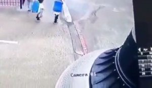 Deux enfants font une prise de catch  à leur mère à la sortie de l'école