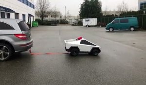 Un mini cybertruck conduit par un enfant tire une voiture