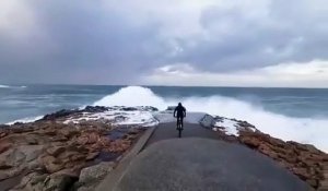 Ce cycliste se rapproche un peu trop près du bord de mer pendant la tempête en Espagne