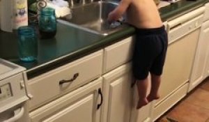 Cet enfant fait la vaisselle bien calé sur son ventre