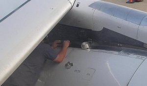 Un technicien fait une réparation au scotch sur un réacteur d'avion