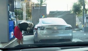 Une femme tente de mettre de l'essence dans une Tesla