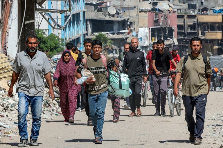 Des Palestiniens marchent le 14 mai 2024, au milieu de bâtiments détruits, dans une rue de Jabaliya, dans le nord de la bande de Gaza, où une guerre oppose Israël au mouvement islamiste palestinien Hamas