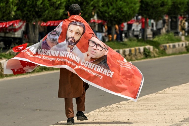 Un partisan de la Conférence Nationale porte une bannière avec des photos de dirigeants du parti lors d'un meeting de campagne électorale à Srinagar, la principale ville du Cachemire administrée par l'Inde, le 11 mai 2024