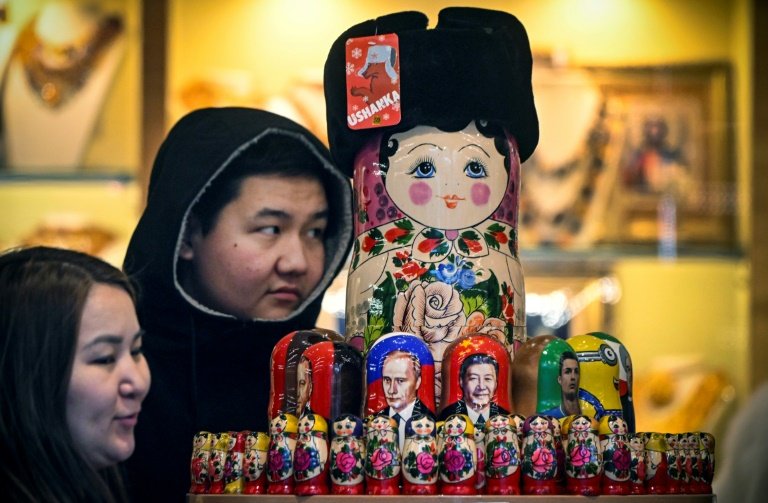 Des touristes regardent des poupées russes à l'effigie de Xi Jinping et Vladimir Poutine, à Moscou le 15 novembre 2023