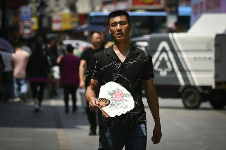 Des passants par une chaude journée à Pékin, le 11 juin 2024
