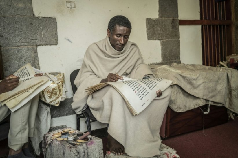 Zelalem Mola, prêtre orthodoxe éthiopien copie un livre religieux sur un parchemin, à l'institut Hamere Berhan d'Addis Abeba, en Ethiopie, le 17 mai 2023